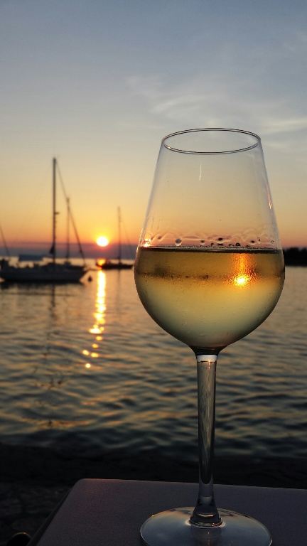 Mit einem Glas Wein den Sonnenuntergang genießen